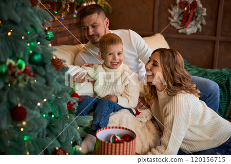Happy family decorate the Christmas tree and smiling cheerfully on Christmas Eve in a beautiful home 120156715