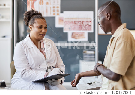 Side view portrait of smiling female doctor holding clipboard while consulting patient complaining of skin rash and allergies 120157061
