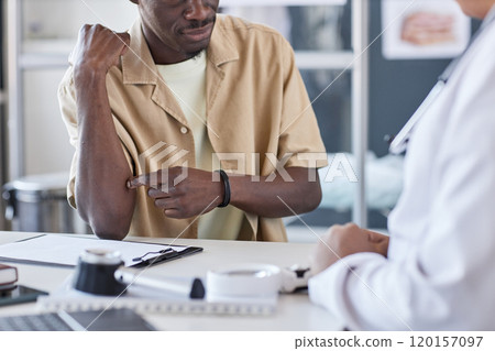 Cropped shot of unrecognizable African American man pointing at skin rash spots on arms and elbow while explaining psoriasis symptoms to dermatologist copy space 120157097