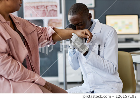 Portrait of senior African American doctor using dermascope while inspecting skin of patient during examination in clinic copy space 120157192