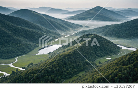 A winding river flows through a valley surrounded by misty mountains, creating a peaceful scene A winding river flows through a valley surrounded by misty mountains, creating a peaceful scene 120157207