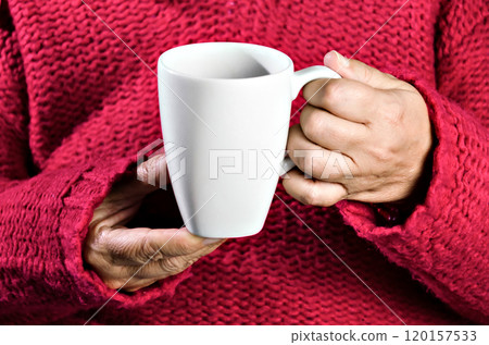 Adult woman with red sweater holding a cup of latte coffee Adult woman with red sweater holding a cup of latte coffee 120157533