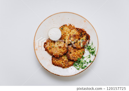 Crispy potato pancakes with sour cream and fresh greens, perfect as a savory side or appetizer Crispy potato pancakes with sour cream and fresh greens, perfect as a savory side or appetizer 120157725
