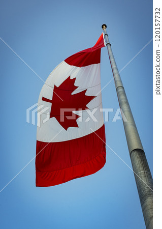 Canada flag hanging limply from tall flagpole Canada flag hanging limply from tall flagpole 120157732