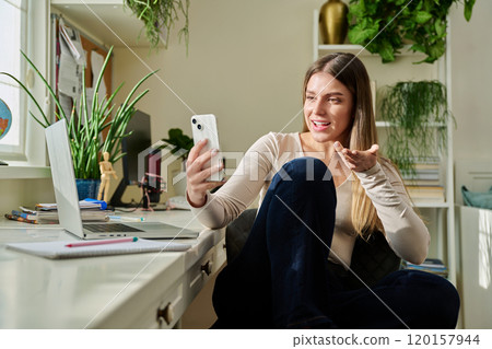 Young woman with smartphone at home having video call Young woman with smartphone at home having video call 120157944