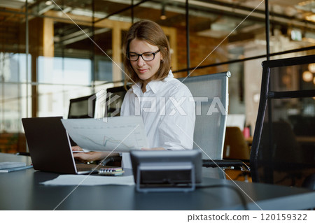 A Professional Woman is Working Diligently in a Modern Office with Her Laptop Open A Professional Woman is Working Diligently in a Modern Office with Her Laptop Open 120159322