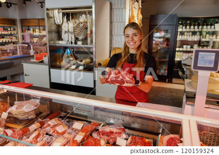 The Friendly Butcher at a Modern Meat Shop Displaying a Selection of Fresh Cuts of Meat The Friendly Butcher at a Modern Meat Shop Displaying a Selection of Fresh Cuts of Meat 120159324