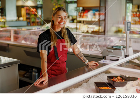Cheerful Smiling Fishmonger Enthusiastically Working at Seafood Counter in Local Market 120159330