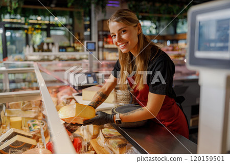 A cheerful employee at a cheese shop is enthusiastically smiling while serving happy customers A cheerful employee at a cheese shop is enthusiastically smiling while serving happy customers 120159501