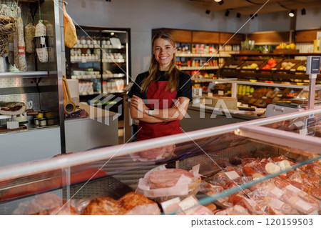 A Cheerful and Smiling Female Butcher Working in a Modern Meat Shop Environment A Cheerful and Smiling Female Butcher Working in a Modern Meat Shop Environment 120159503