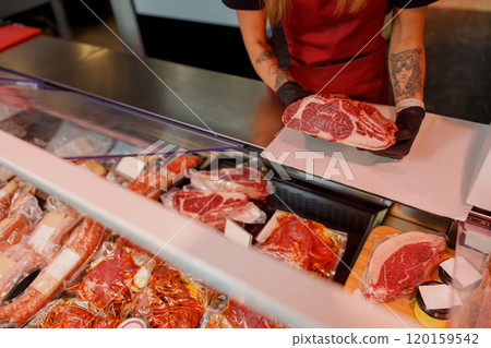 A skilled butcher is meticulously preparing fresh, highquality meat in a local shop A skilled butcher is meticulously preparing fresh, highquality meat in a local shop 120159542