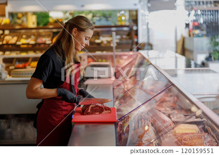 Expert Butcher Skillfully Preparing Fresh Meat in a Modern Deli Market Environment 120159551