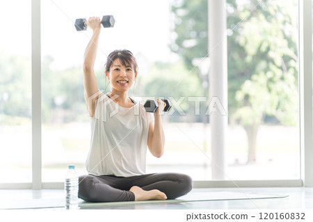 Asian woman in sportswear doing muscle training with dumbbells at the gym 120160832