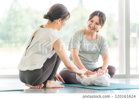 A pregnant woman and her female instructor attending maternity yoga/pre-mom yoga 120161624
