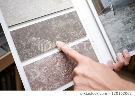 Designer hand pointing at stone tile sample on display catalog Designer hand pointing at stone tile sample on display catalog 120162062