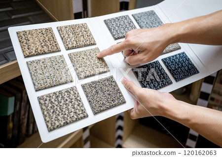 Designer hand pointing at sample fabric pieces on carpet swatch collection Designer hand pointing at sample fabric pieces on carpet swatch collection 120162063