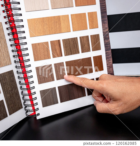 Designer hand pointing at wooden laminate swatch collection in material sample catalog Designer hand pointing at wooden laminate swatch collection in material sample catalog 120162085