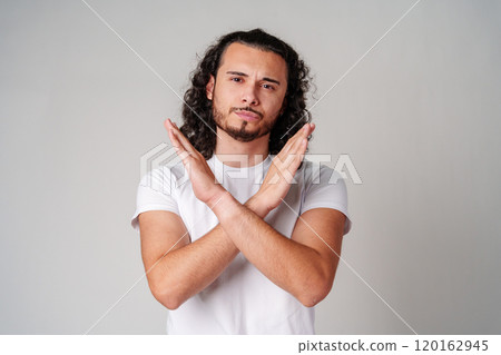 Man expressing disagreement with crossed arms gesture against a neutral background 120162945