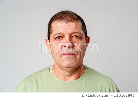 A mature man stands against a plain background, showcasing a calm expression A mature man stands against a plain background, showcasing a calm expression 120162948
