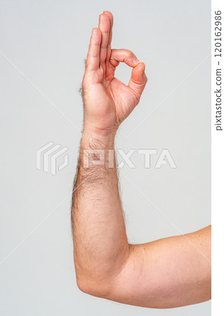 A person demonstrates the okay hand gesture with a raised arm against a plain background A person demonstrates the okay hand gesture with a raised arm against a plain background 120162986