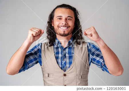 Happy man celebrating success with raised fists in a studio against a plain background 120163001