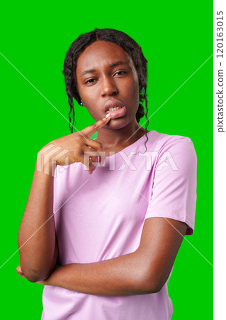 Thoughtful woman pondering in front of a bright green background during a casual moment 120163015