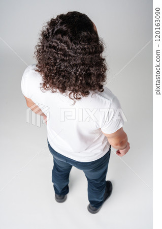 Person with curly hair facing away, wearing a plain white shirt in a minimalist studio Person with curly hair facing away, wearing a plain white shirt in a minimalist studio 120163090
