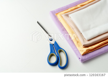 Crafting supplies arranged on a table with scissors and folded fabric in various colors 120163167