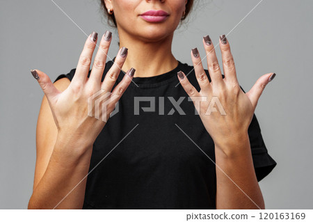 A woman showcasing chic nail art with modern design in a casual setting 120163169