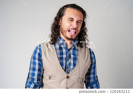 Man making a silly face with tongue out in casual attire against a neutral background 120163212