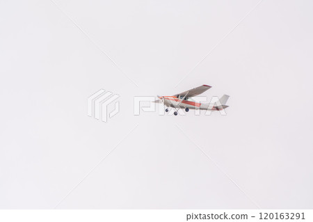 Small ultralight airplane with overhead wing and single propeller flying in sunset sky. 120163291