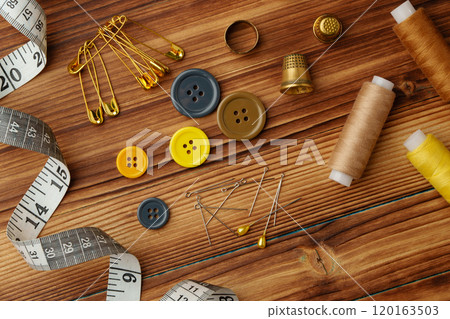 Crafting tools and materials arranged on a wooden table for sewing projects Crafting tools and materials arranged on a wooden table for sewing projects 120163503