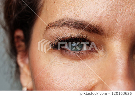 Close-up view of a woman's striking blue eyes with long lashes 120163626