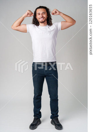 Happy man celebrating success with raised fists in a studio against a plain background Happy man celebrating success with raised fists in a studio against a plain background 120163655