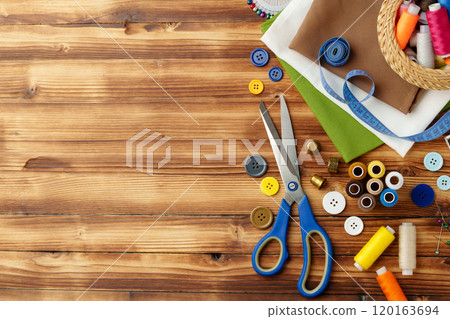 Crafting tools and materials arranged on a wooden table for sewing projects 120163694