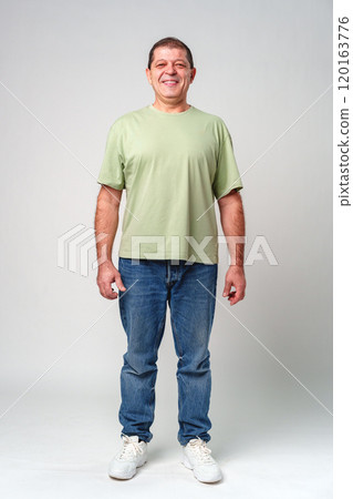 Smiling middle-aged man with short hair in a light green shirt against a simple backdrop 120163776