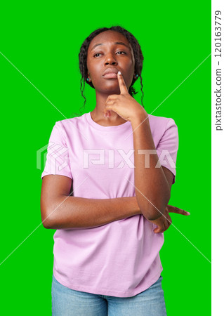 Thoughtful woman pondering in front of a bright green background during a casual moment 120163779