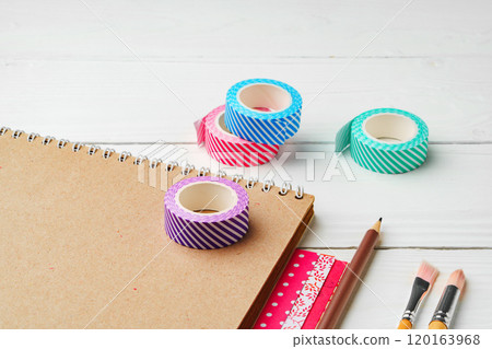 Crafting inspiration with colored pencils, decorative tape, and playful shapes on a rustic wooden surface 120163968