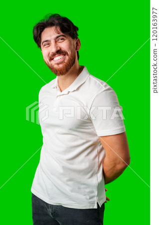 A smiling young man with a beard poses against a bright green background A smiling young man with a beard poses against a bright green background 120163977