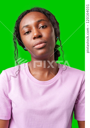 Young woman with an expression of contemplation poses against a bright green background Young woman with an expression of contemplation poses against a bright green background 120164031