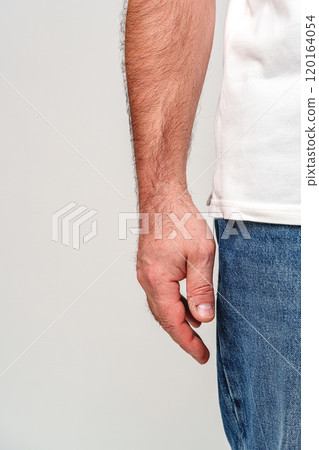A close-up view of a man's bare hand resting against his side A close-up view of a man's bare hand resting against his side 120164054