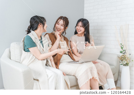Women, friends, mom friends, and colleagues using laptops at home with friends (laughing, having fun) 120164428