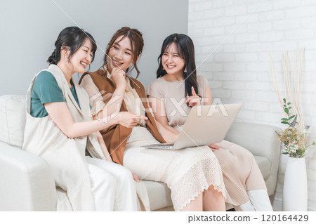 Women, friends, mom friends, and colleagues using laptops at home with friends (laughing, having fun) 120164429