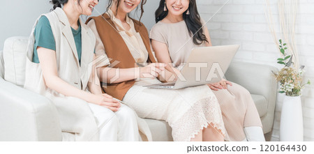 Women, friends, mom friends, and colleagues using laptops at home with friends 120164430