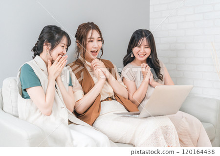 Women, friends, mom friends, and colleagues using laptops at home with friends 120164438