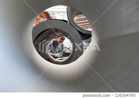 Young asian worker in a factory check large rolls of metal. Safety equipment is worn for protection. Young asian worker in a factory check large rolls of metal. Safety equipment is worn for protection. 120164795