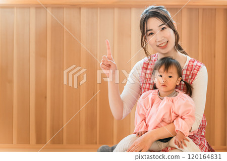 A young Asian woman, a nursery teacher, holding a toddler girl 120164831