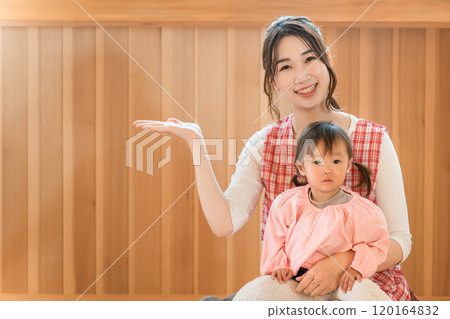 A young Asian woman, a nursery teacher, holding a toddler girl A young Asian woman, a nursery teacher, holding a toddler girl 120164832