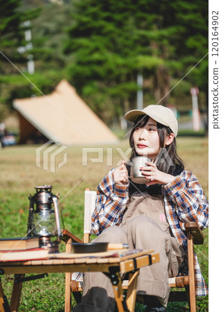 Young woman having a drink in camp Young woman having a drink in camp 120164902