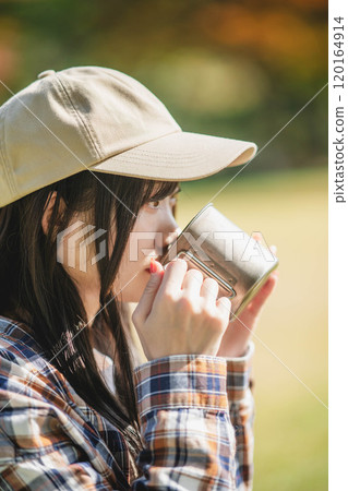 Young woman having a drink in camp Young woman having a drink in camp 120164914